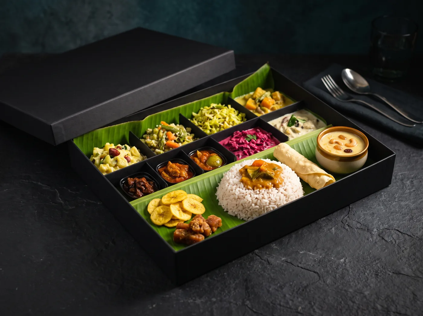 Onam Sadya laid out on a banana leaf inside a takeaway box